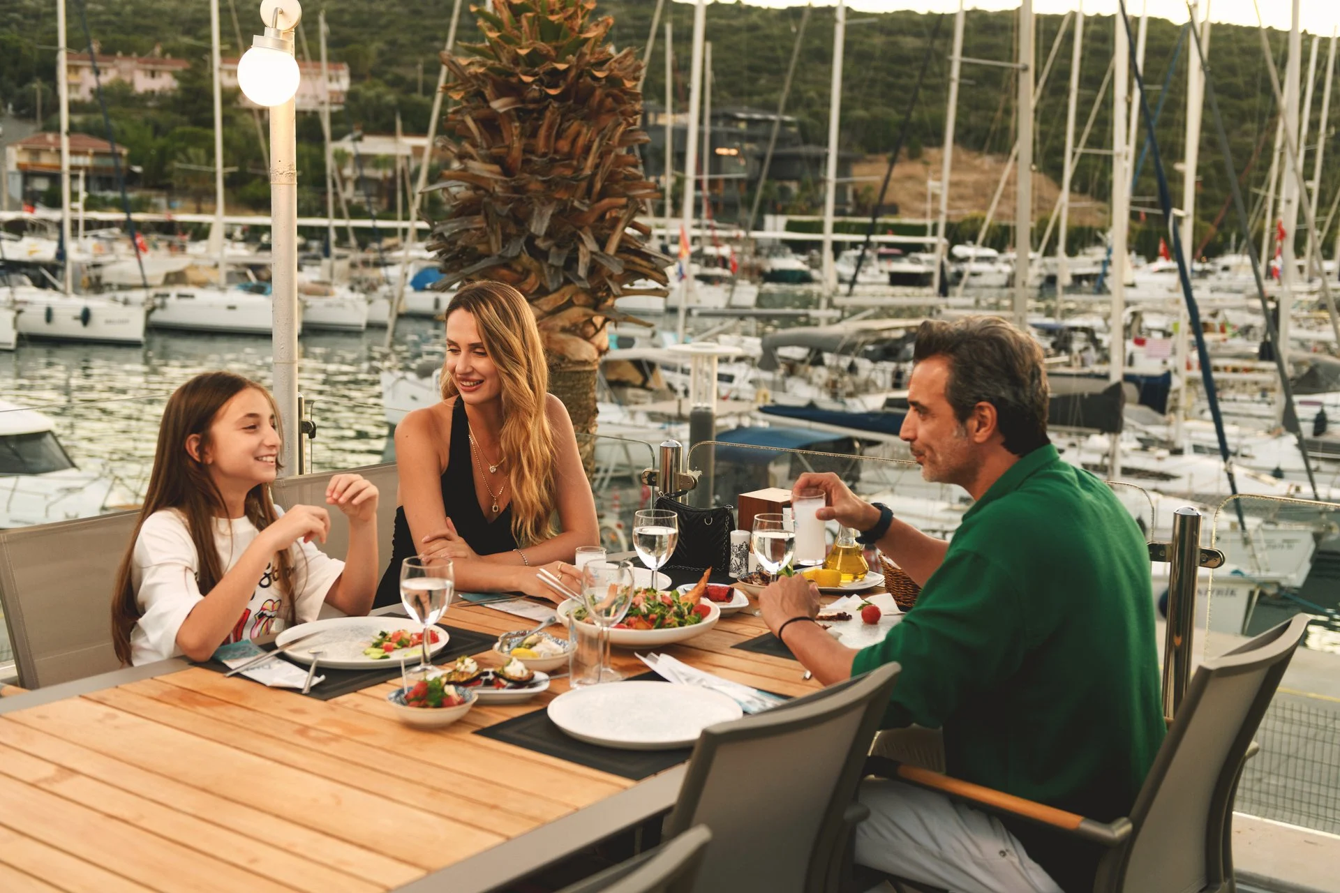 Famille dégustant mezze et rakı dans un restaurant de marina au coucher du soleil